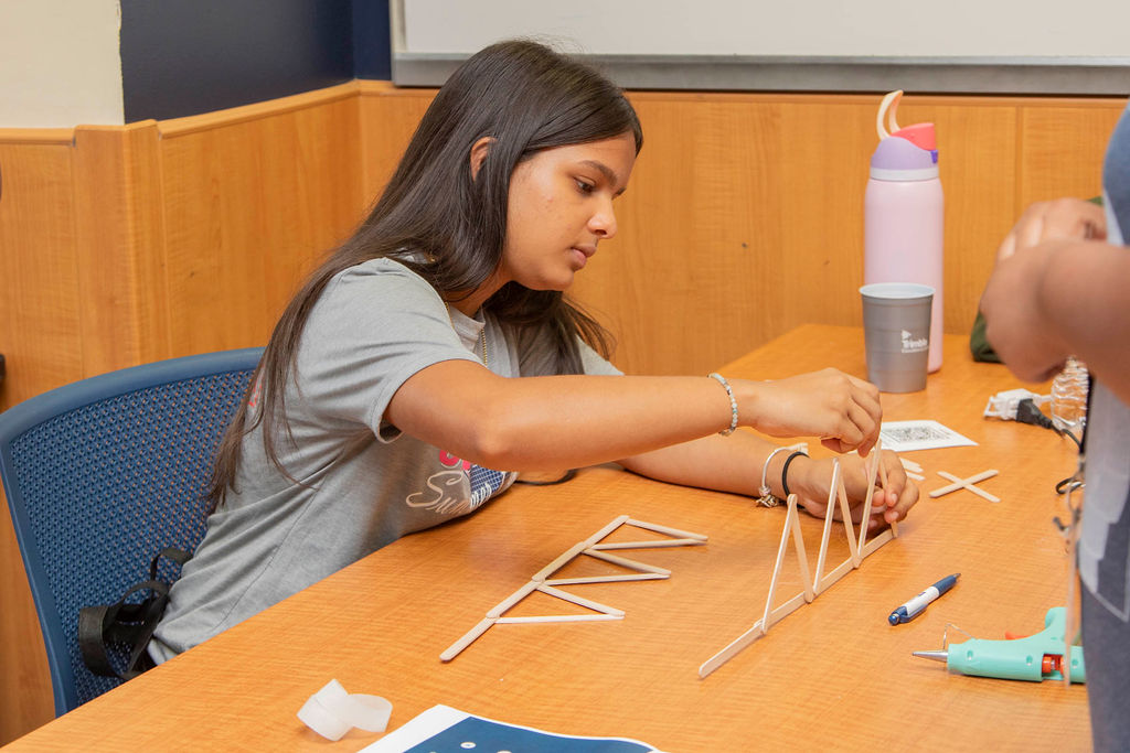 A younger Trimble Boot Camp students builds a bridge with sticks