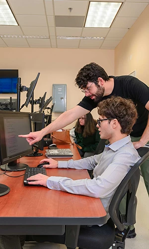 FIU CEC student instructing another at a computer