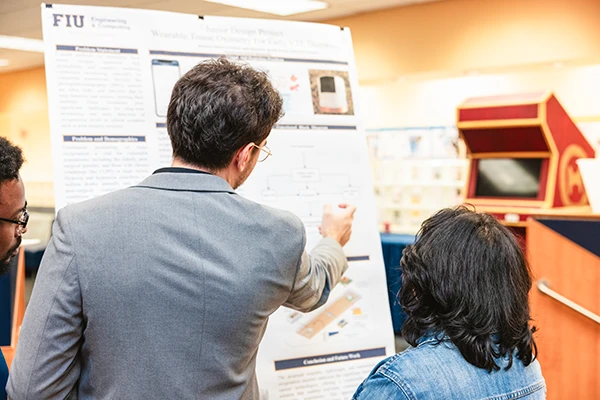 FIU CEC student pointing at poster during Senior Design Showcase