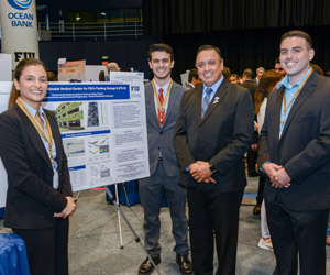 Students standing with professor at Senior Showcase next to poster presentation
