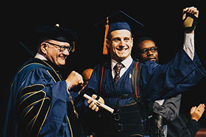Aldo Amenta walks across commencement stage for his Master’s